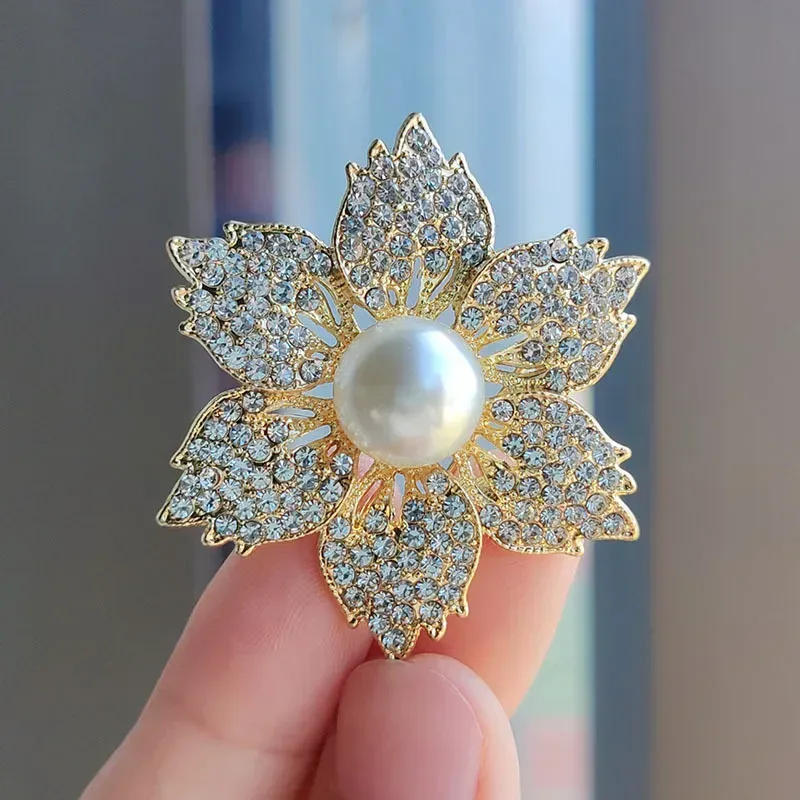 faux pearl flower brooch shown in the hand for size