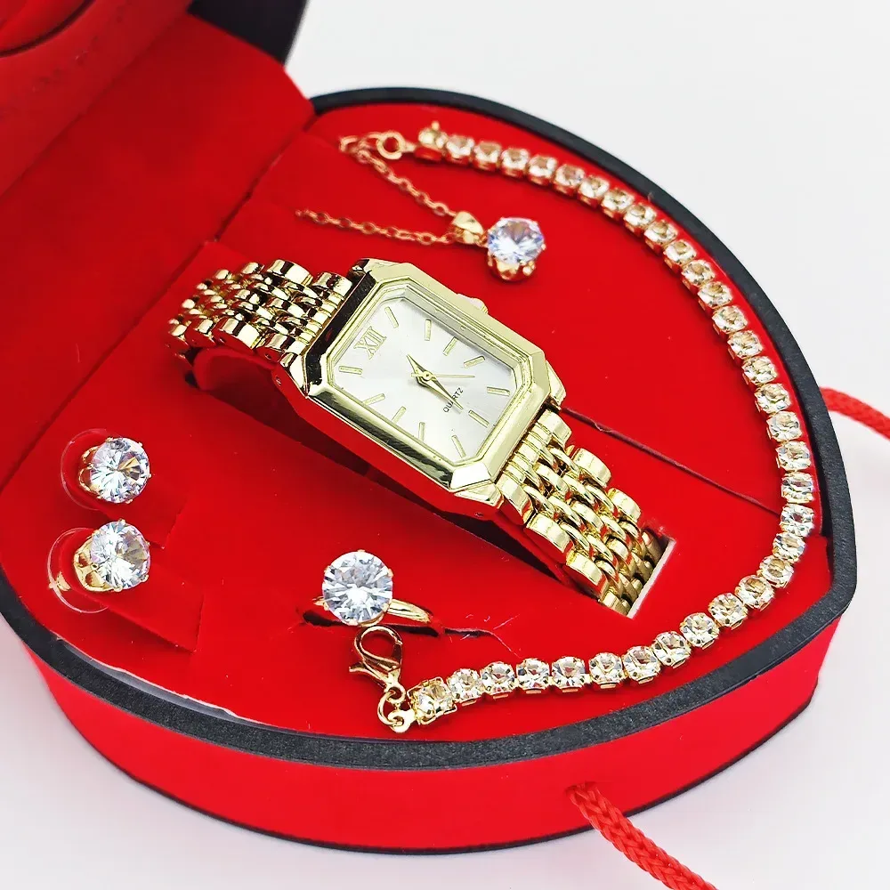 gold tone rectangular watch with white dial beside rhinestone bracelet and ring