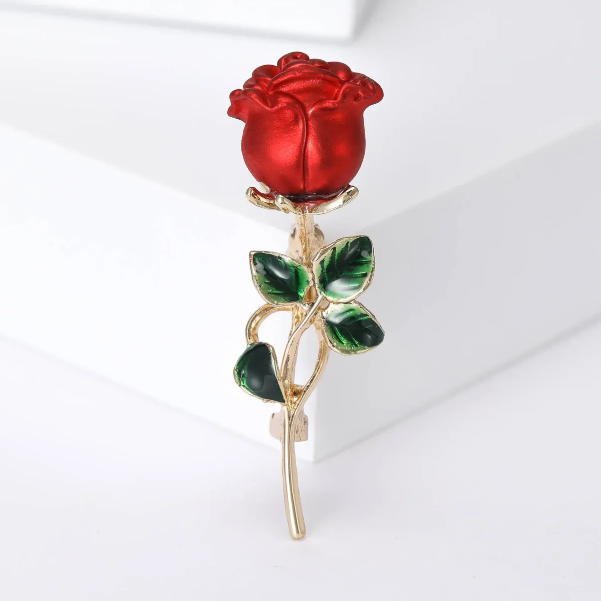 red rose brooch with green leaves on a gold-tone stem