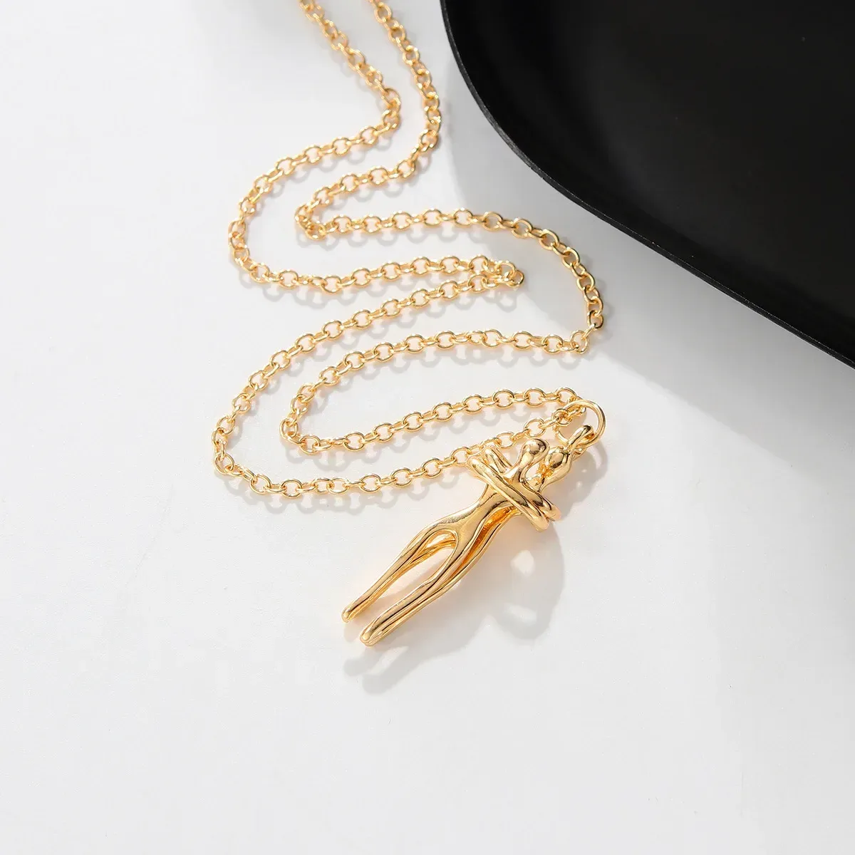 gold tone embracing couple pendant with the chain coiled