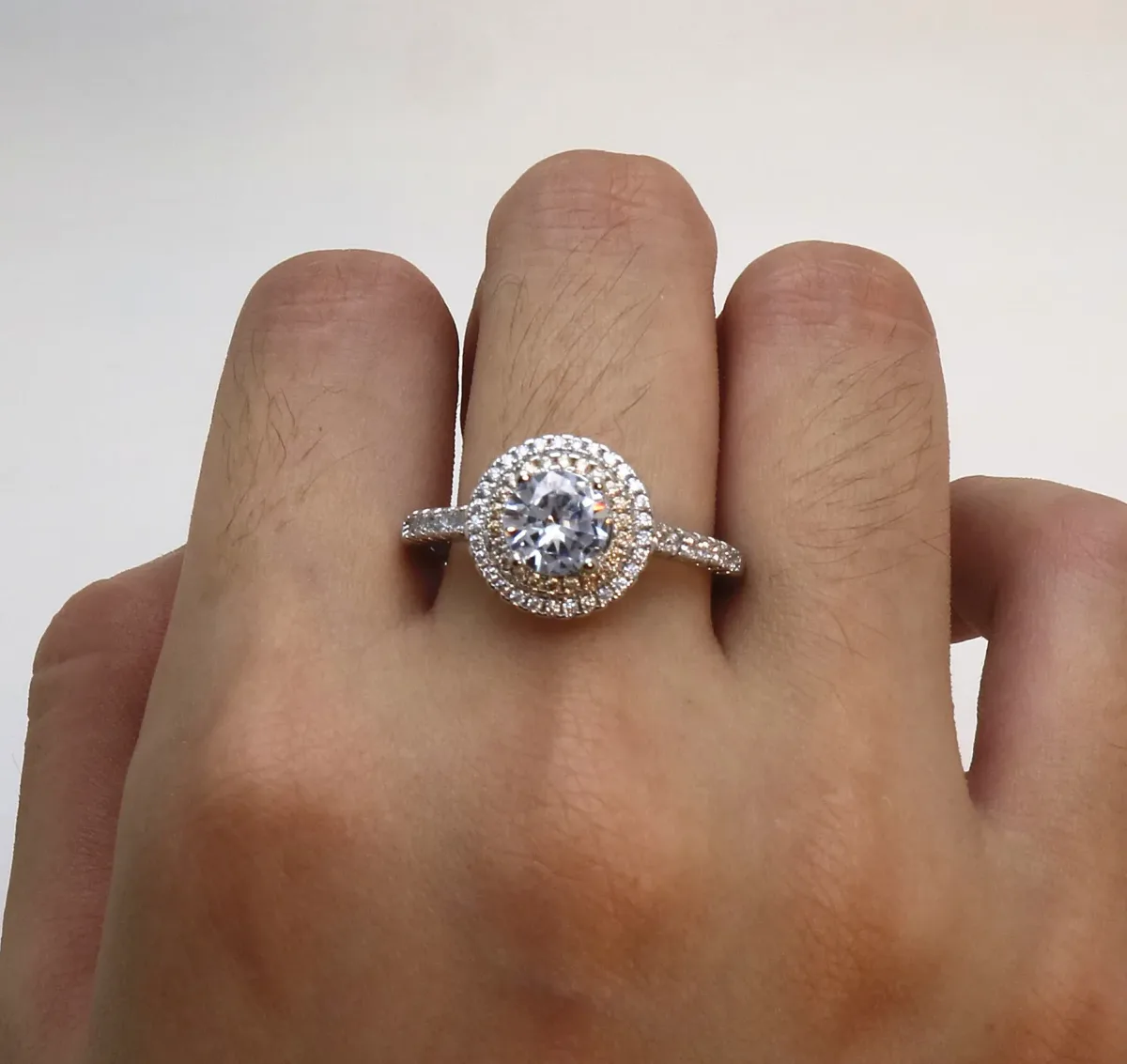 round halo cubic zirconia engagement ring worn on the hand, champagne halo