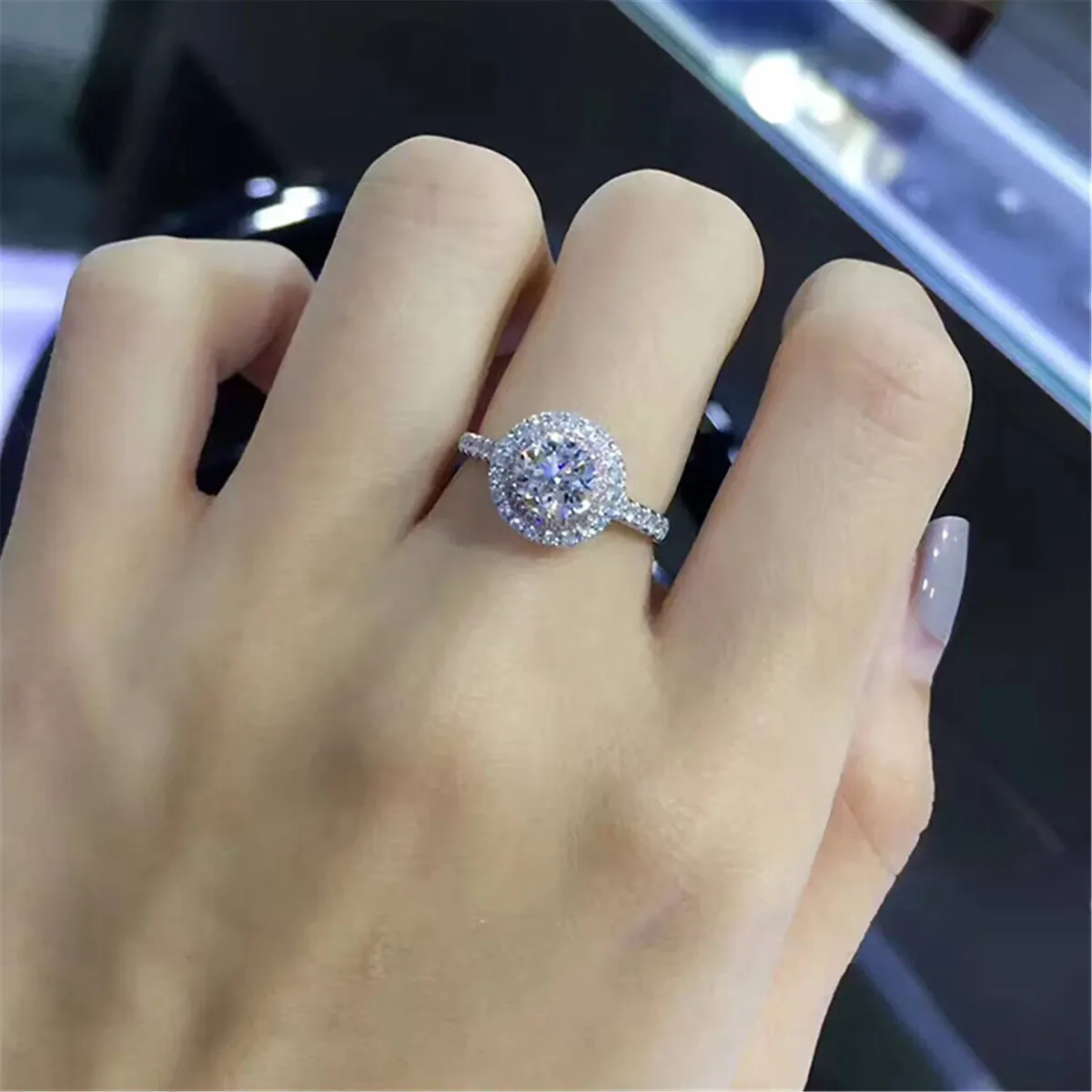 round halo cubic zirconia engagement ring worn on the hand, pink halo