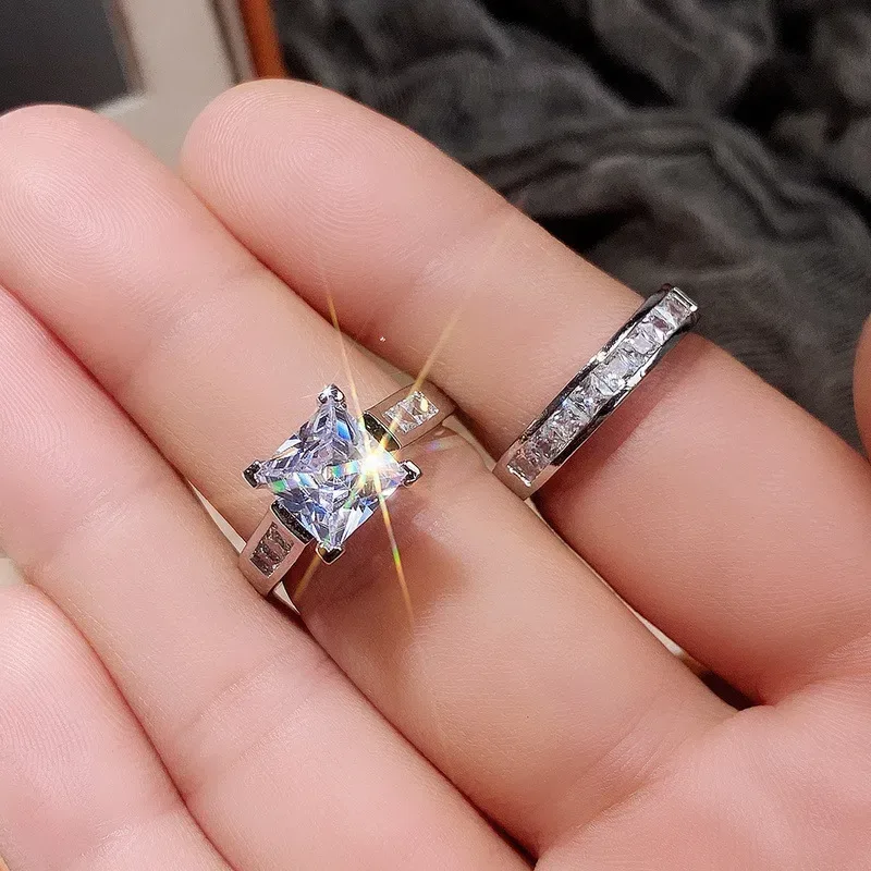 princess cut cubic zirconia engagement ring and band on an open hand for scale